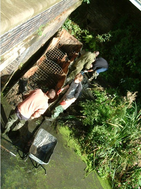 Volunteers pair up to transport and shovel silt into the bastion.